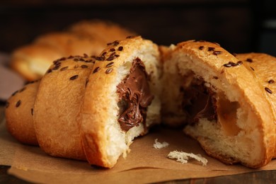 Photo of Tasty croissant with chocolate and sesame seeds on parchment, closeup