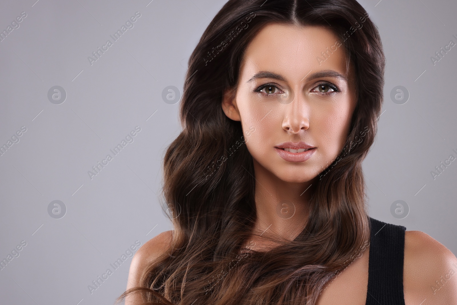 Image of Gorgeous woman with shiny wavy hair on grey background, space for text. Professional hairstyling