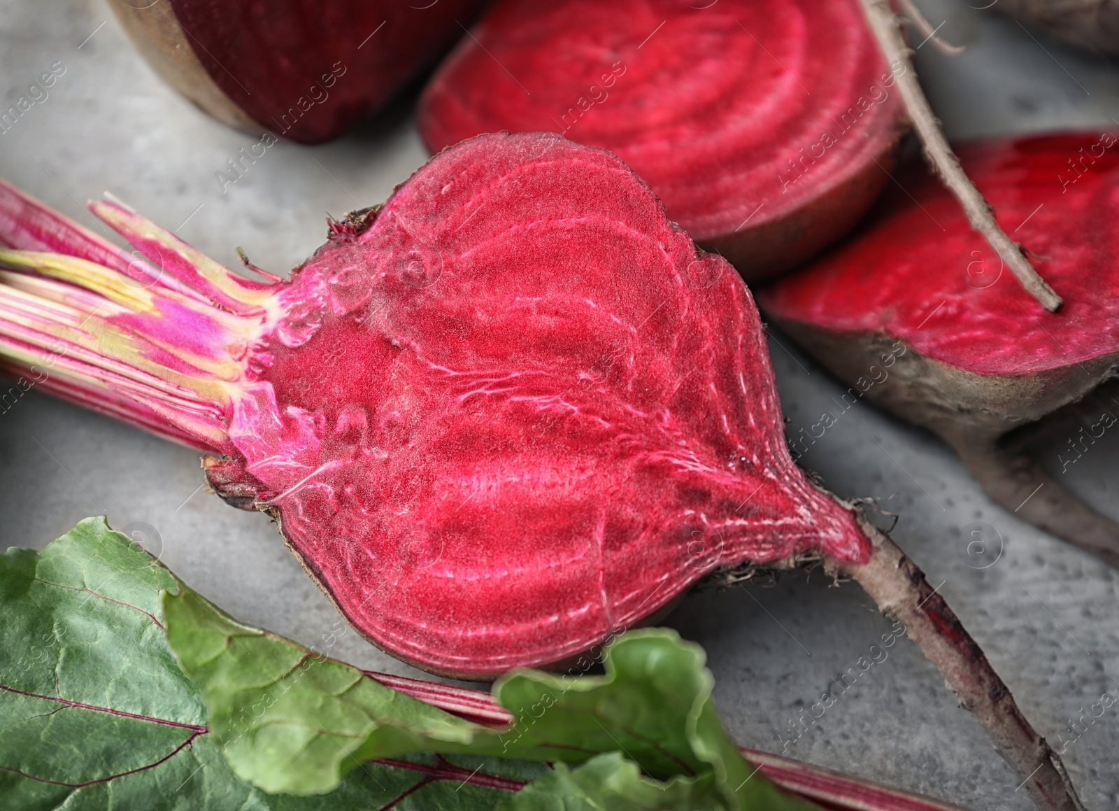 Photo of Cut raw beets on light grey table, closeup