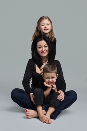 Photo of Little children with their mother on grey background