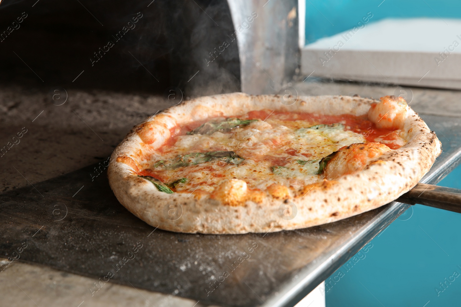 Photo of Taking out tasty pizza from oven in restaurant kitchen