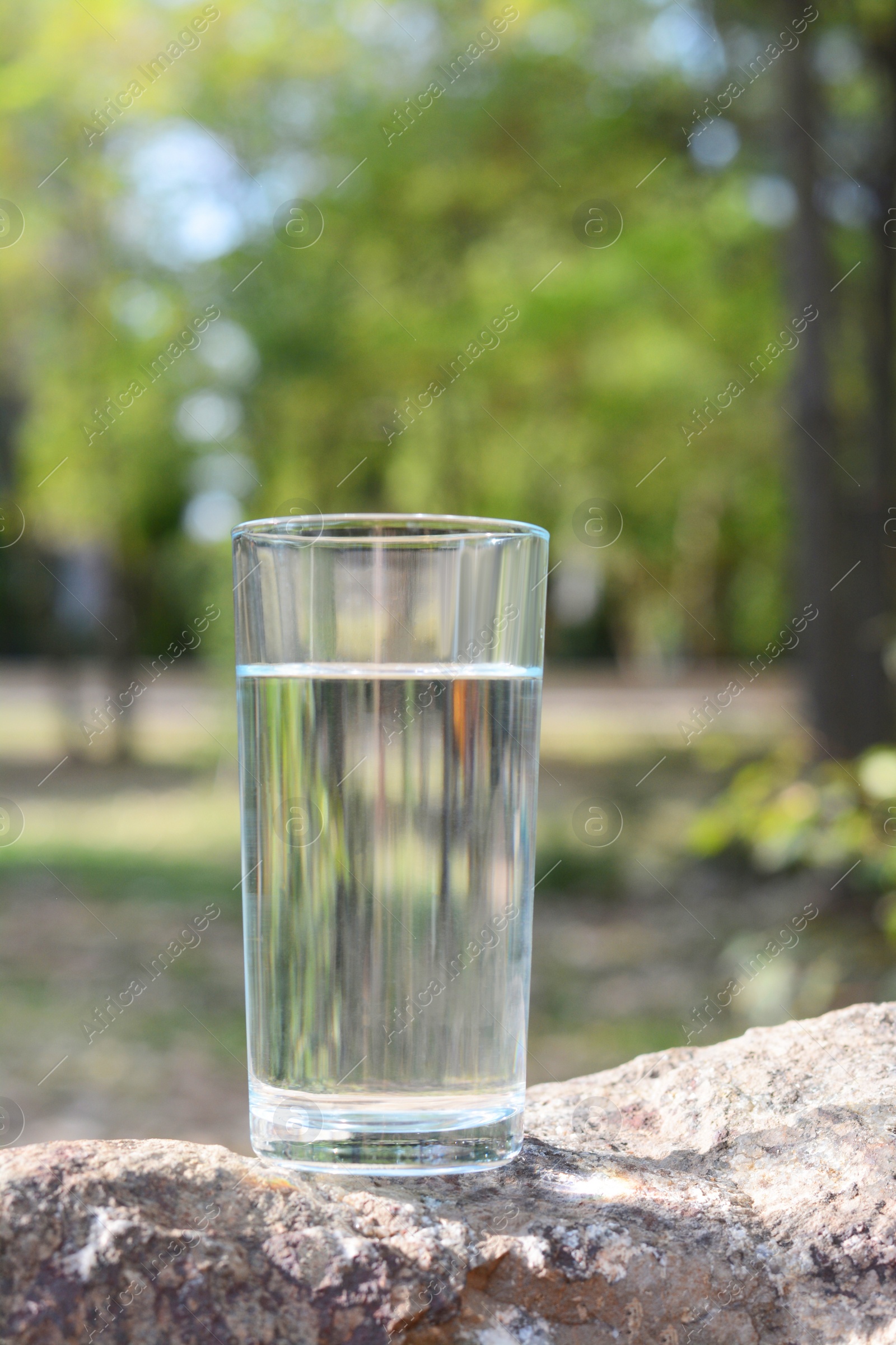 Photo of Glass of cool water on stone outdoors