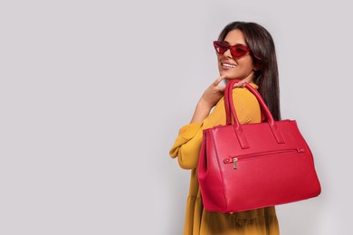 Young woman with stylish bag on white background, space for text