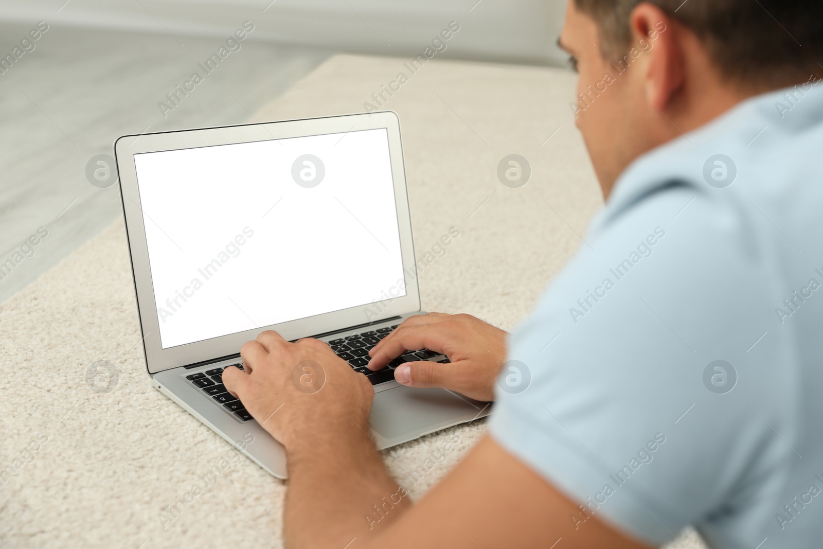 Photo of Man using laptop for search on floor indoors, closeup