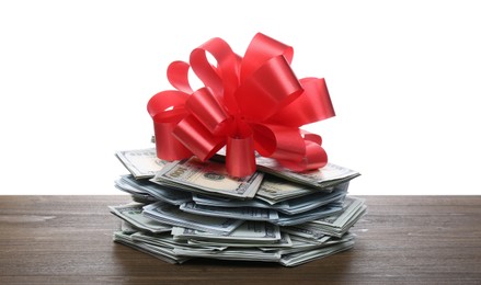Photo of Pile of dollar bills with red bow on wooden table against white background