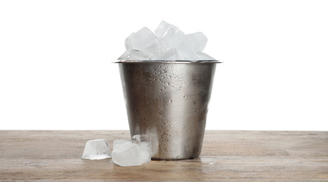 Photo of Metal bucket with ice cubes on wooden table against white background