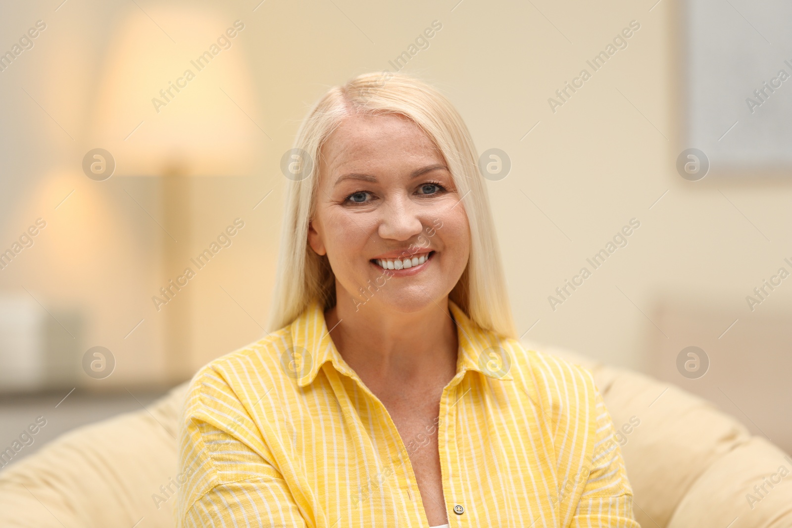 Photo of Portrait of happy mature woman sitting in papasan chair at home