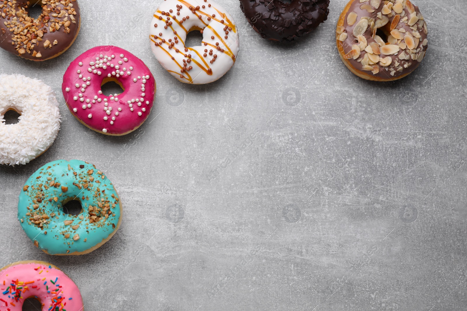 Photo of Different tasty glazed donuts on light grey table, flat lay. Space for text