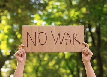 Woman holding poster with words No War in park, closeup