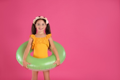 Photo of Cute little child in beachwear with bright inflatable ring on pink background. Space for text