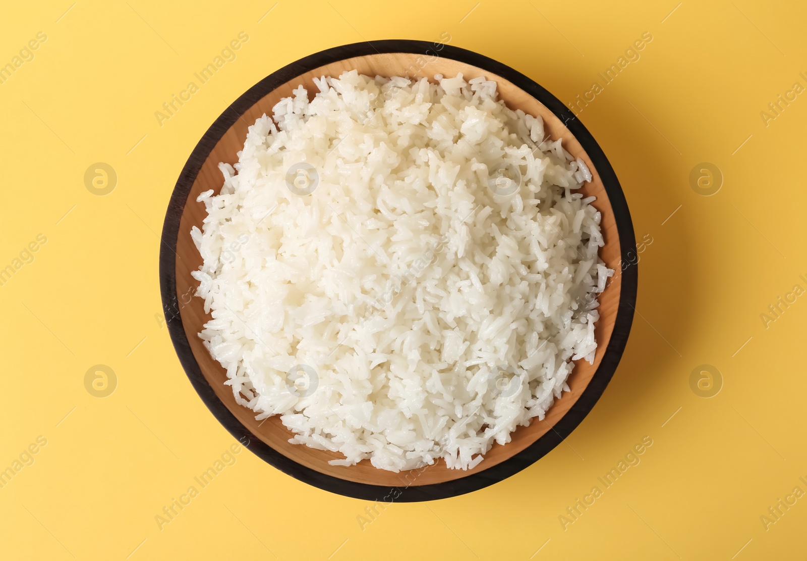 Photo of Bowl of boiled rice on color background, top view