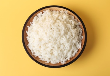 Photo of Bowl of boiled rice on color background, top view