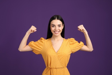 Photo of Strong woman as symbol of girl power on purple background. 8 March concept
