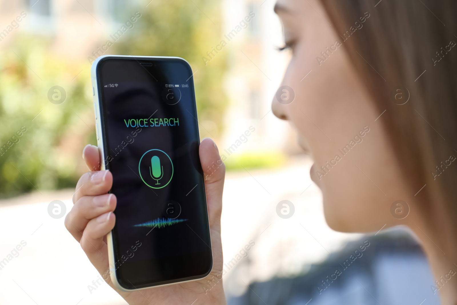 Photo of Woman using voice search on smartphone outdoors, closeup