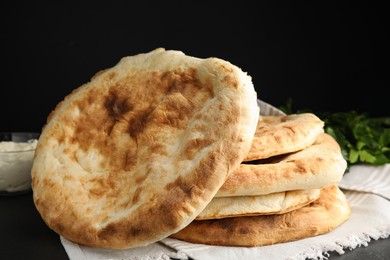 Photo of Delicious fresh pita bread with napkin on black table