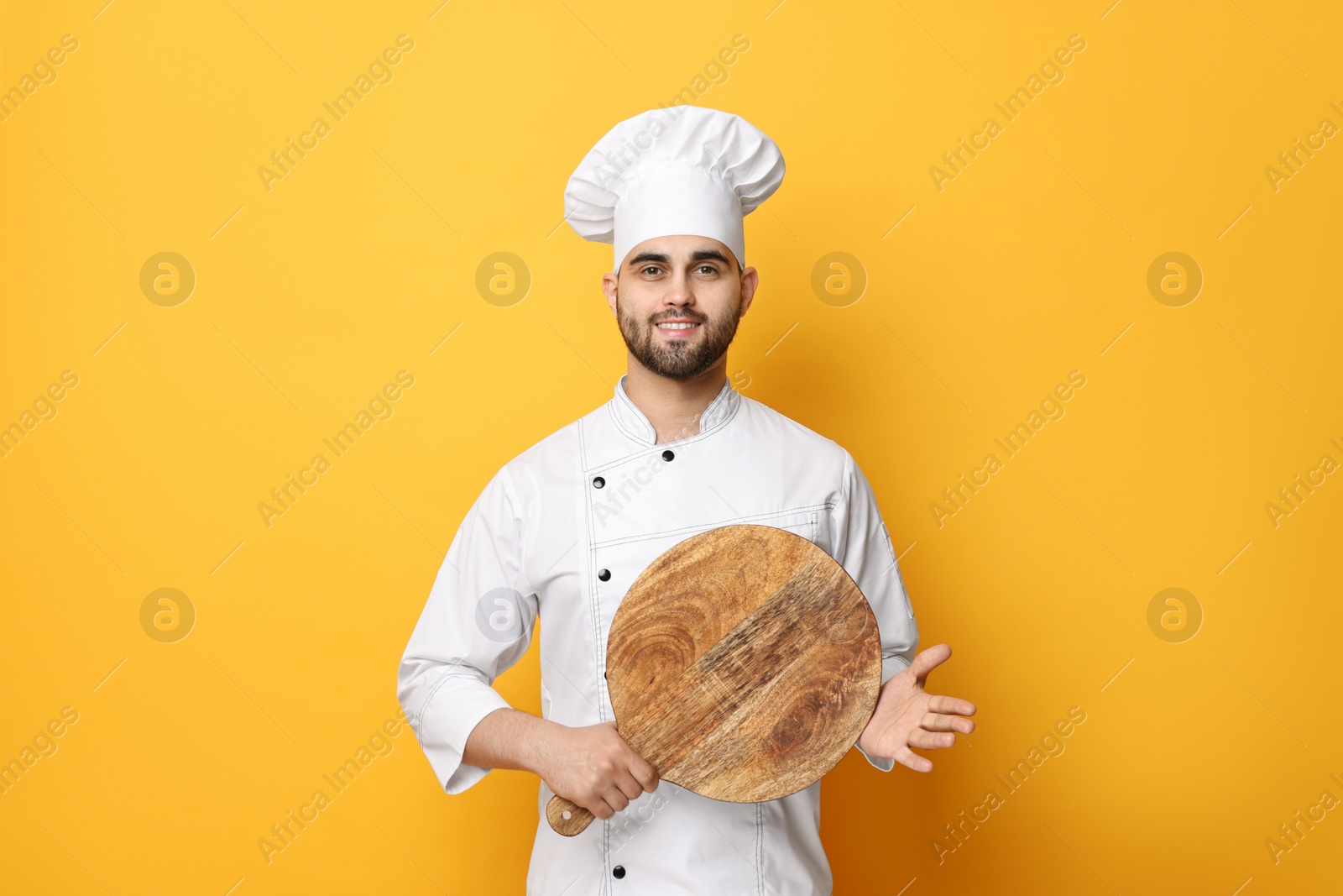 Photo of Professional chef with serving board on yellow background