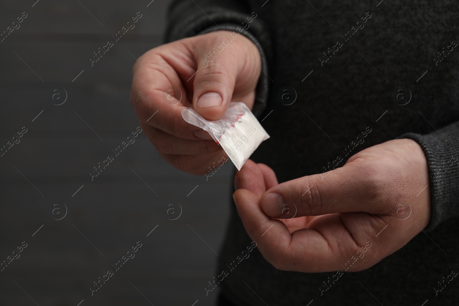 Photo of Addicted man with plastic bag of hard drug on grey background, closeup. Space for text