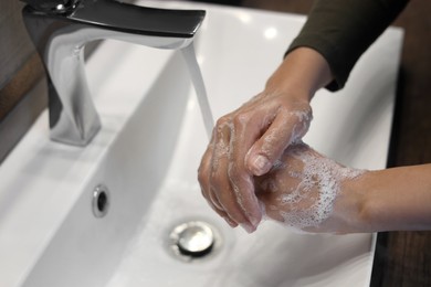 Photo of Woman washing hands in sink, closeup view