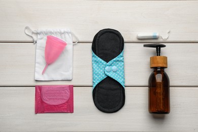 Photo of Cloth menstrual pad and other female hygiene products on white wooden table, flat lay