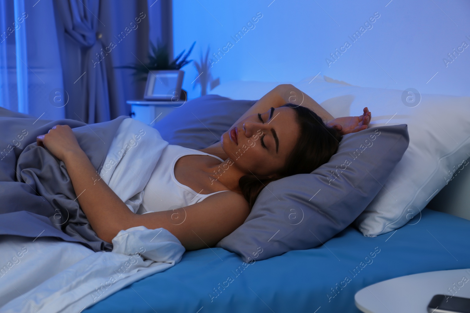 Photo of Young woman sleeping on soft pillow at night. Bedtime