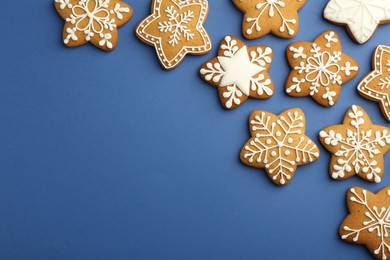 Photo of Tasty star shaped Christmas cookies with icing on blue background, flat lay. Space for text