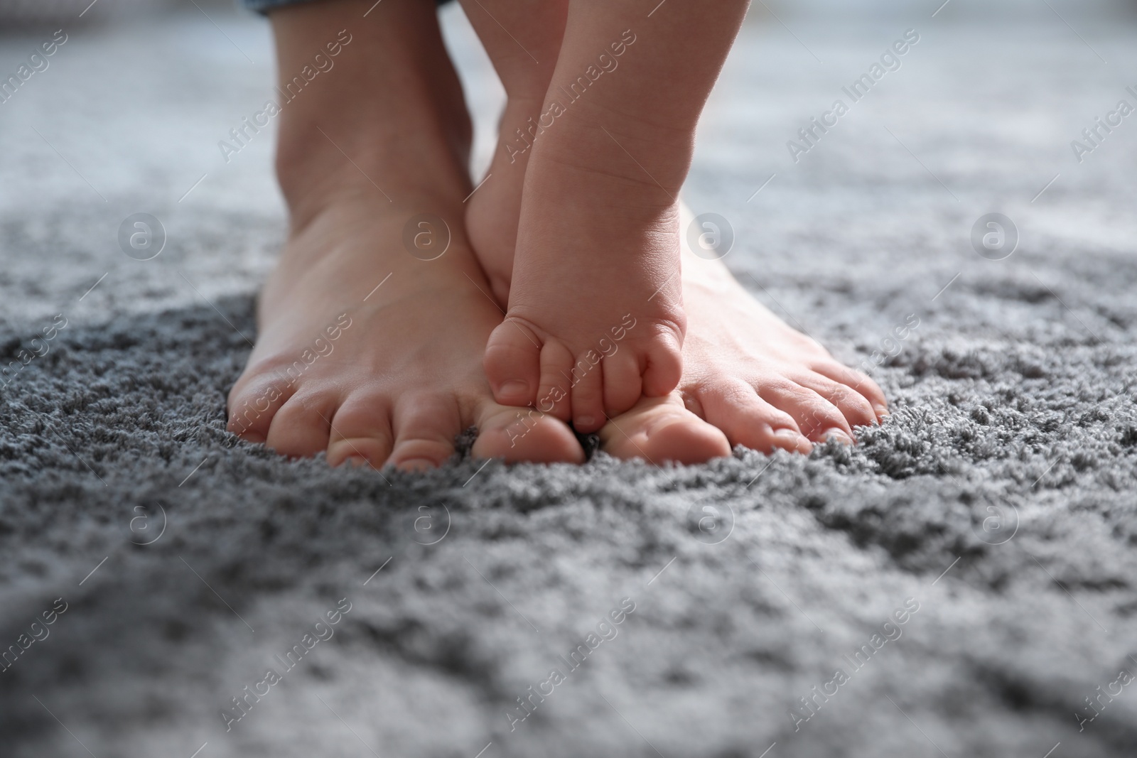 Photo of Baby doing first steps with mother's help, closeup