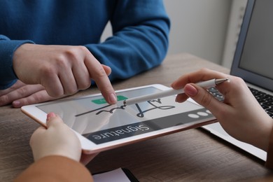 Electronic signature. Man using tablet at wooden table, closeup