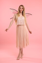 Photo of Beautiful girl in fairy costume with wings on pink background