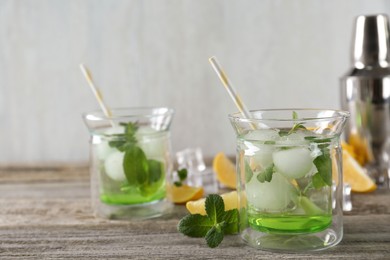 Photo of Delicious cocktails with mint and ice balls on wooden table