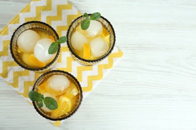 Photo of Delicious cocktails with orange, mint and ice balls on white wooden table, flat lay. Space for text