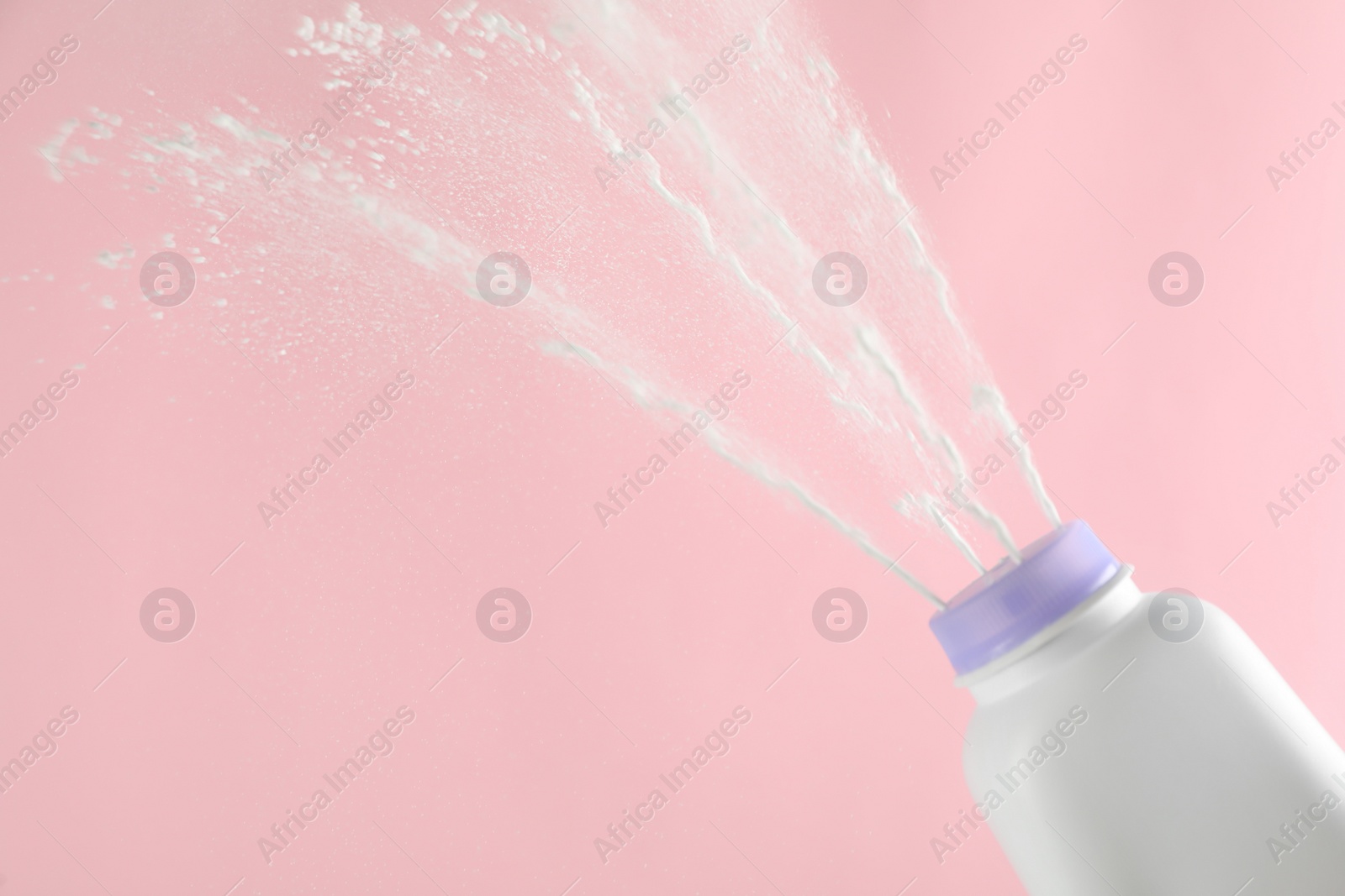 Photo of Scattering of dusting powder on pink background