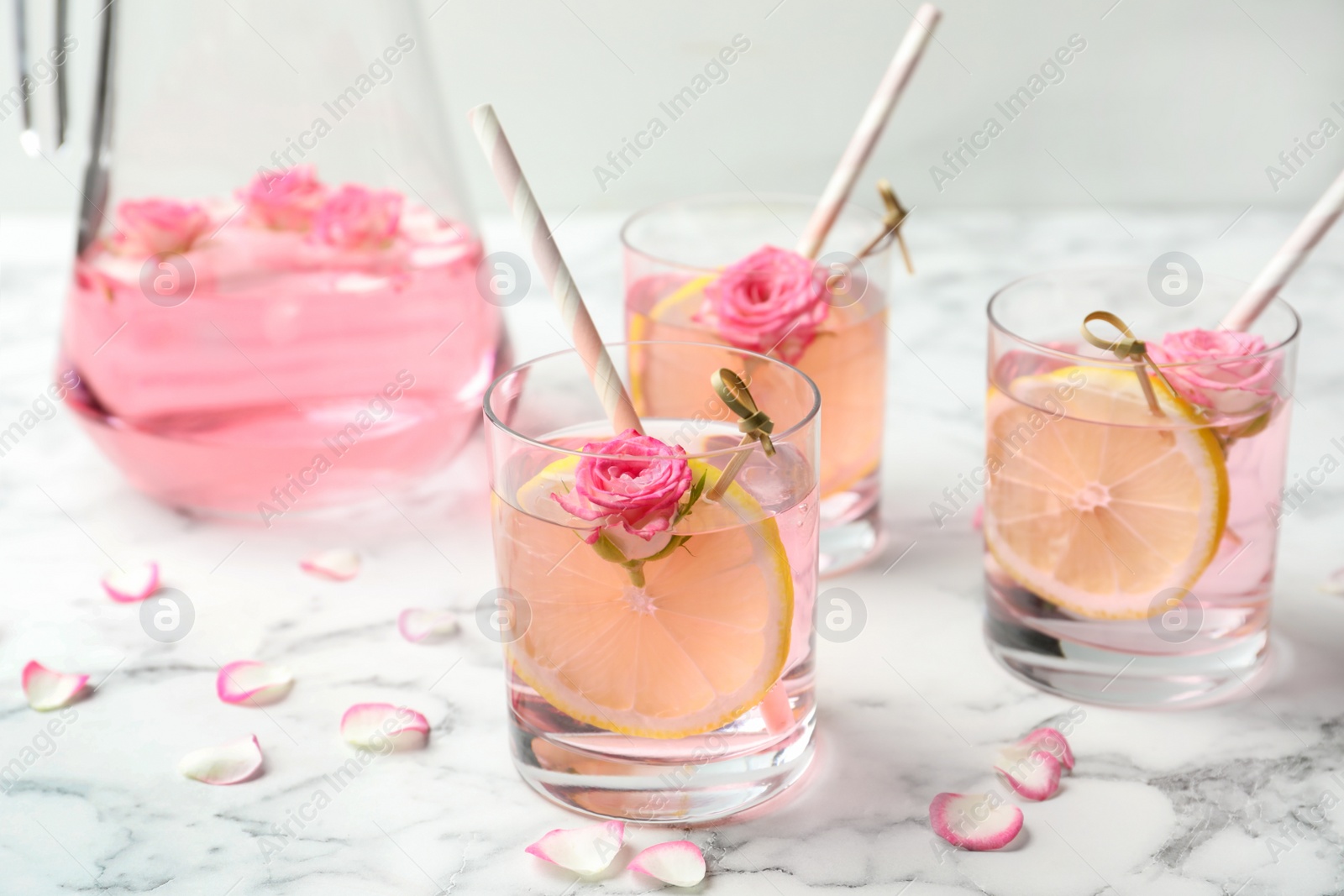Photo of Refreshing drink with lemon and rose on white marble table