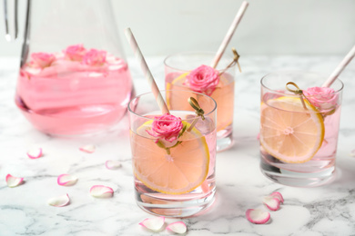 Photo of Refreshing drink with lemon and rose on white marble table