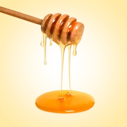 Image of Natural honey dripping from dipper on pale yellow background