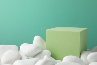 Photo of Presentation for product. Light green cube podium and white pebbles on color background. Space for text