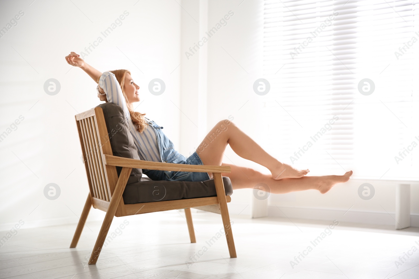 Photo of Young woman relaxing in armchair near window at home