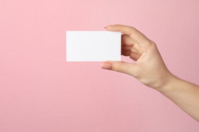 Photo of Woman holding blank business card on pink background, closeup. Mockup for design