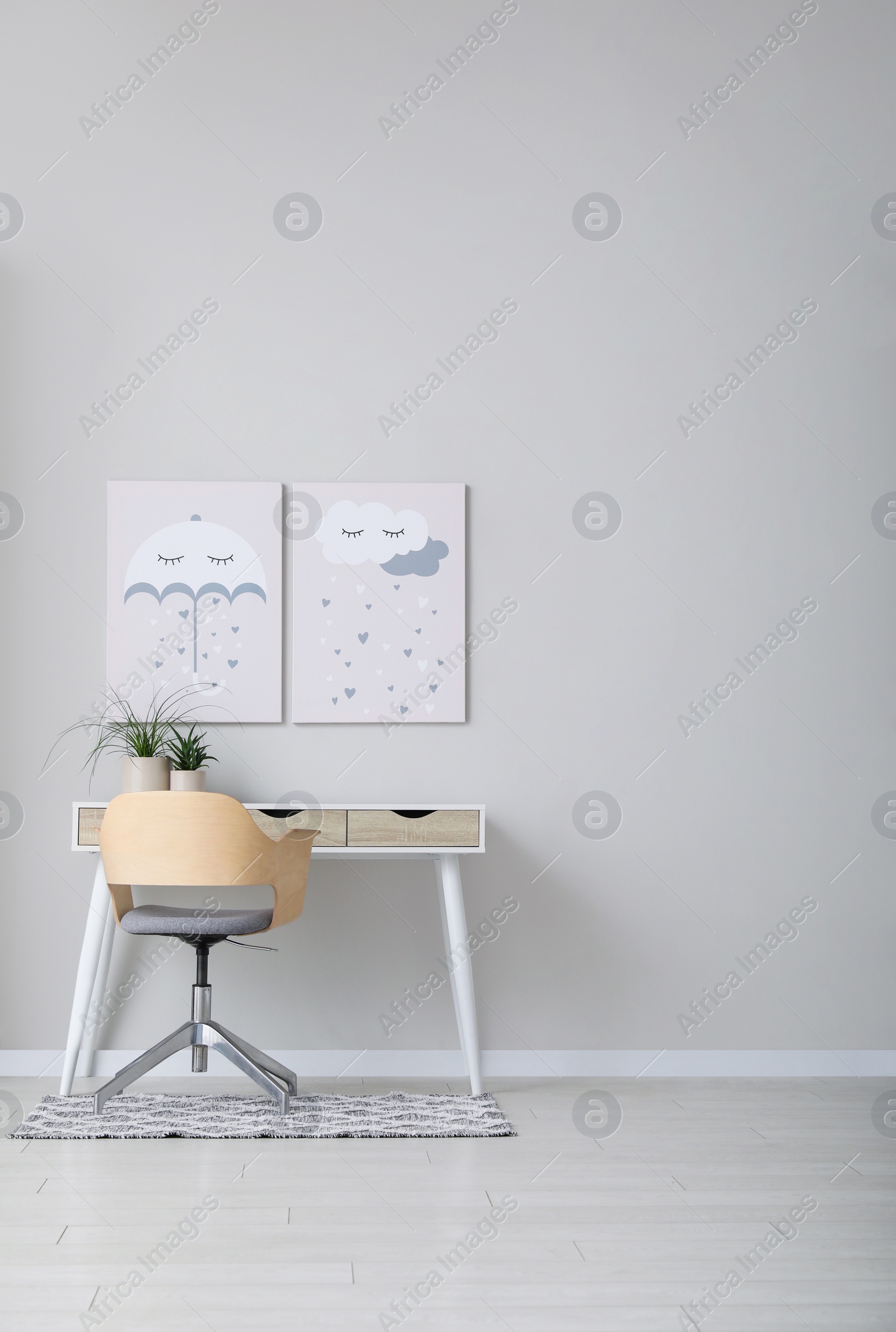 Photo of Children's room interior with desk, cute paintings and empty wall. Space for design