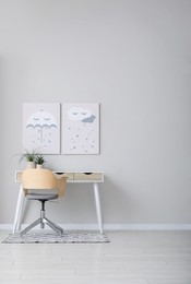 Photo of Children's room interior with desk, cute paintings and empty wall. Space for design