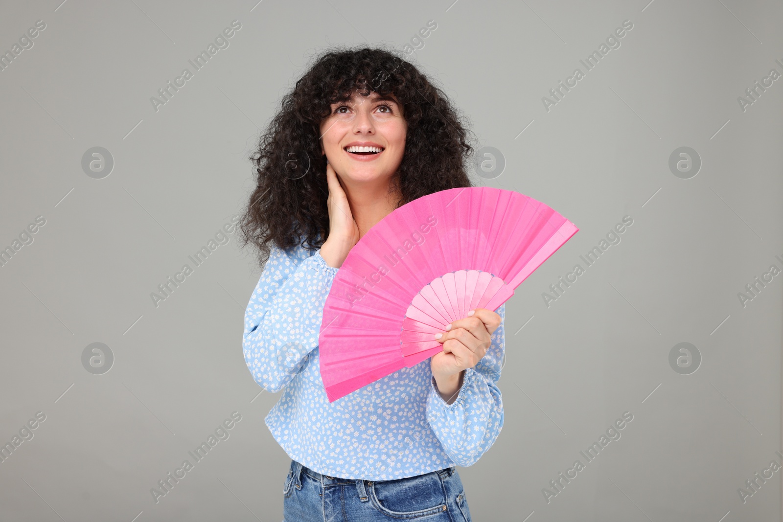 Photo of Happy woman holding hand fan on light grey background