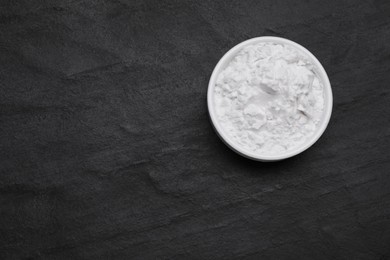 Photo of Bowl of natural starch on black table, top view. Space for text