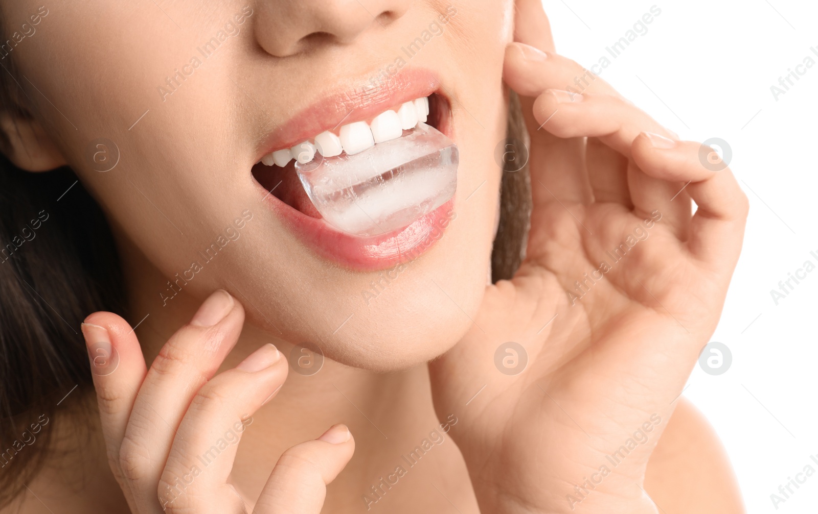 Photo of Young woman holding ice cube in mouth on white background, closeup