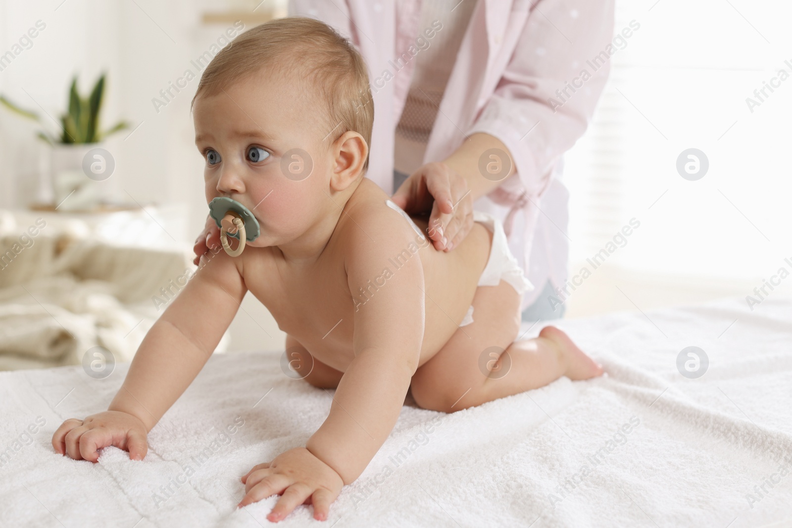 Photo of Mother applying body cream on her little baby at home, closeup