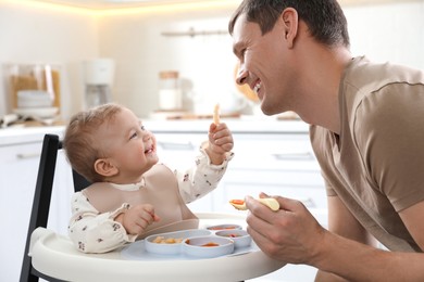 Photo of Father feeding his cute little baby healthy food at home