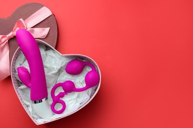 Photo of Gift box with sex toys on red background, top view. Space for text