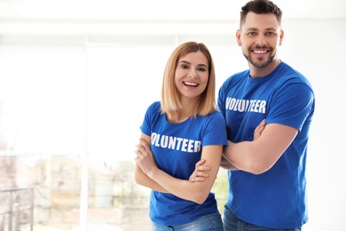 Portrait of happy volunteers in uniform indoors. Space for text