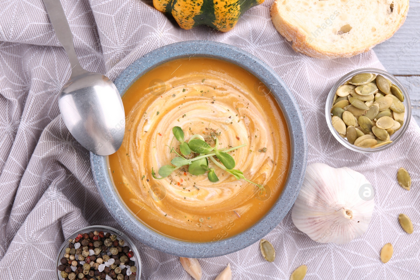 Photo of Tasty pumpkin soup with microgreens served on table, flat lay