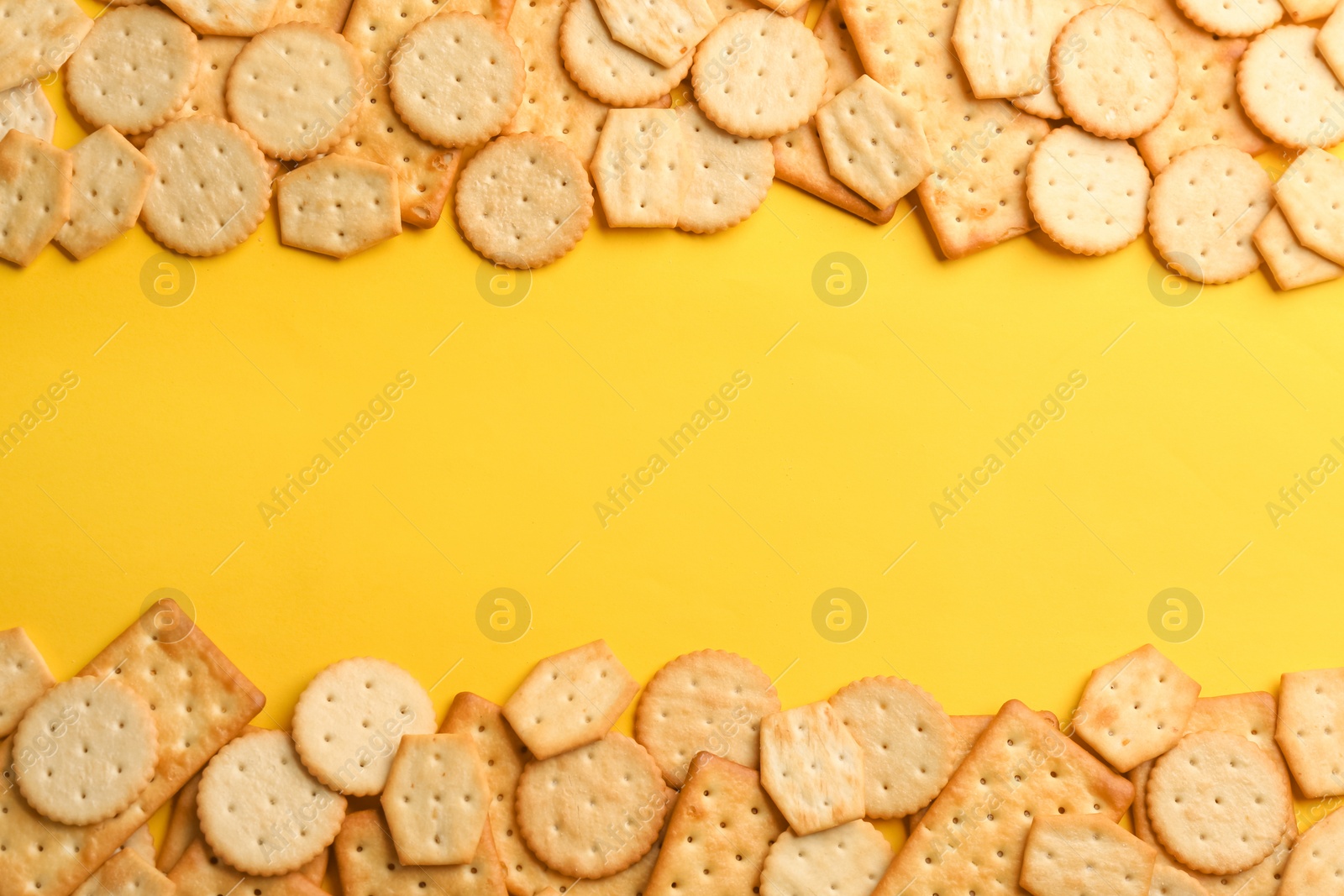 Photo of Delicious crackers on yellow background, flat lay. Space for text