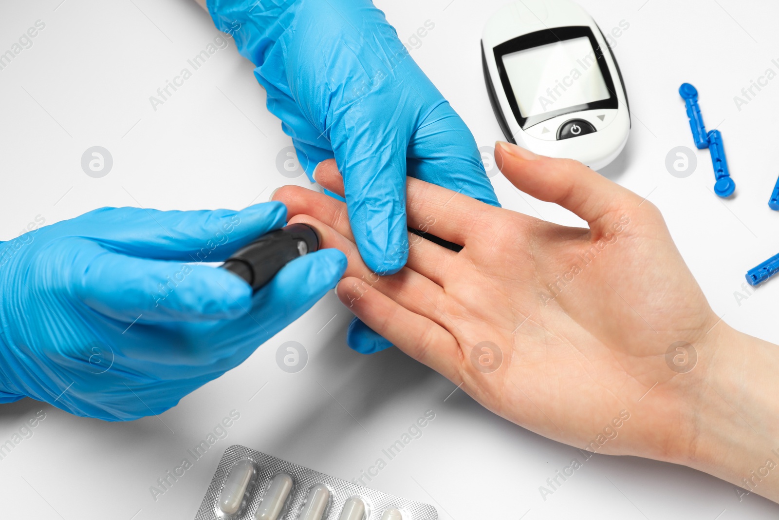 Photo of Diabetes. glucose testing. Doctor using lancet pen on white background, closeup