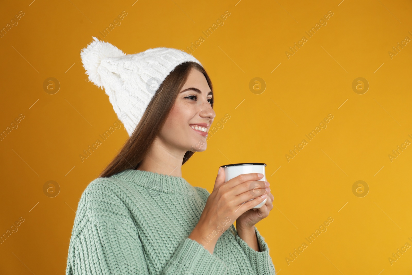 Photo of Happy beautiful woman with mug of mulled wine on yellow background